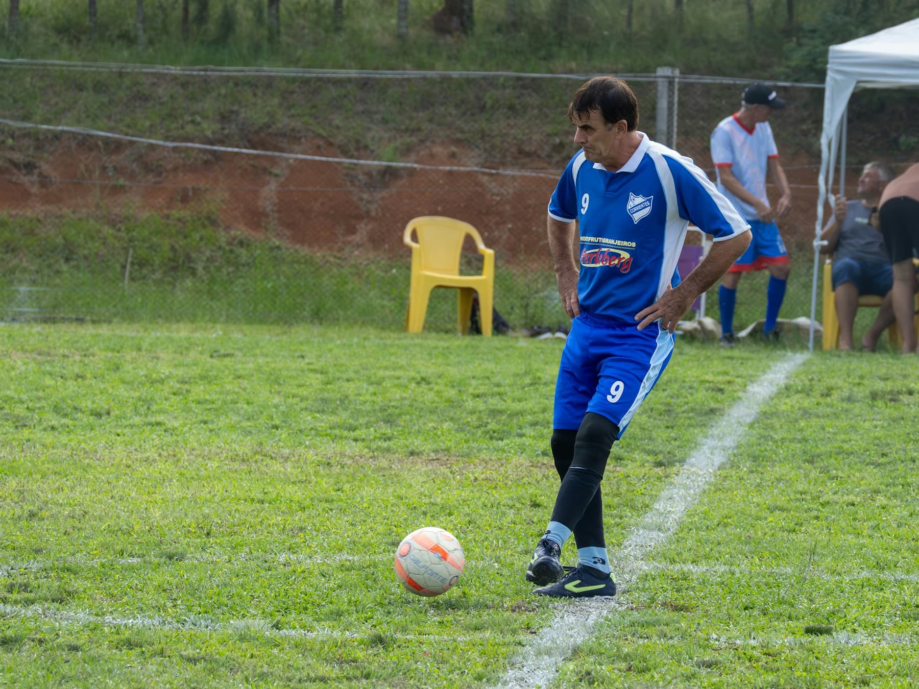 Futbolista de camiseta azul controlando el balón en una cancha